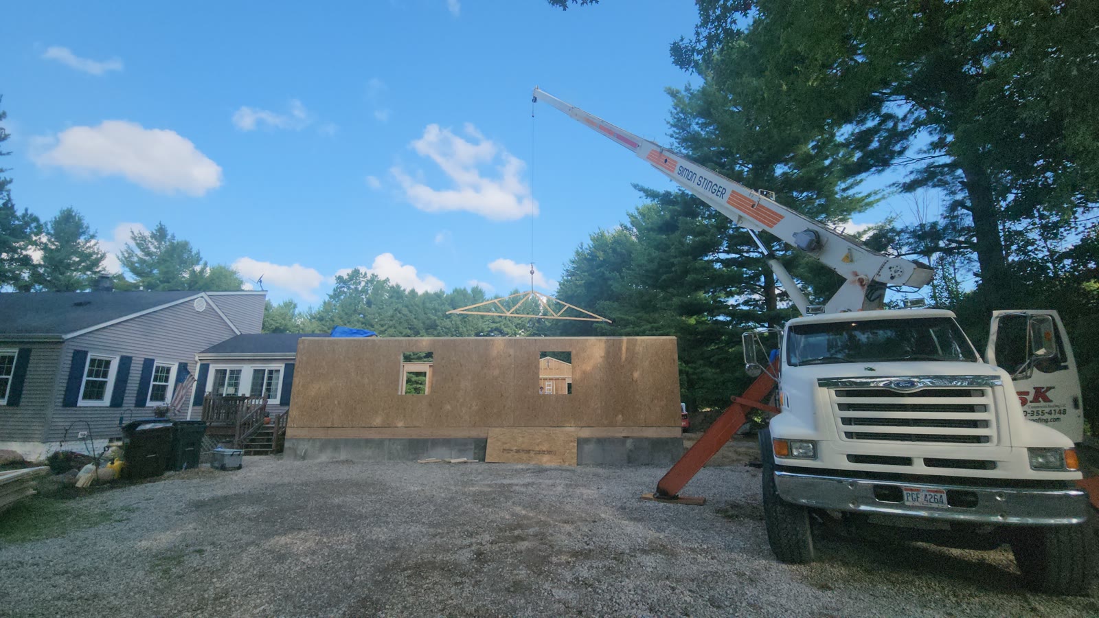Crane setting roof trusses on a framed home addition by Clean Construction LLC, addition contractor serving Amherst and Lorain County Ohio
